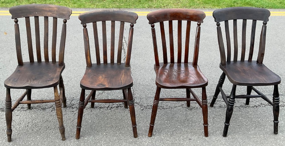 A set of four dark brown Victorian wooden lathback kitchen chairs with turned legs and contoured seats.
