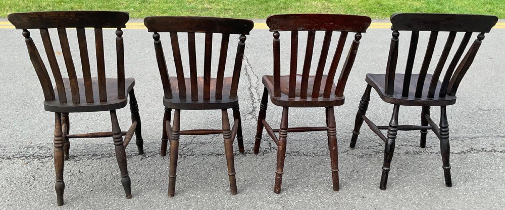 A set of four dark brown Victorian wooden lathback kitchen chairs with turned legs and contoured seats. View V