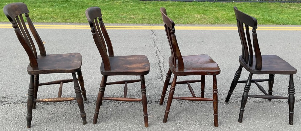 A set of four dark brown Victorian wooden lathback kitchen chairs with turned legs and contoured seats. View VI