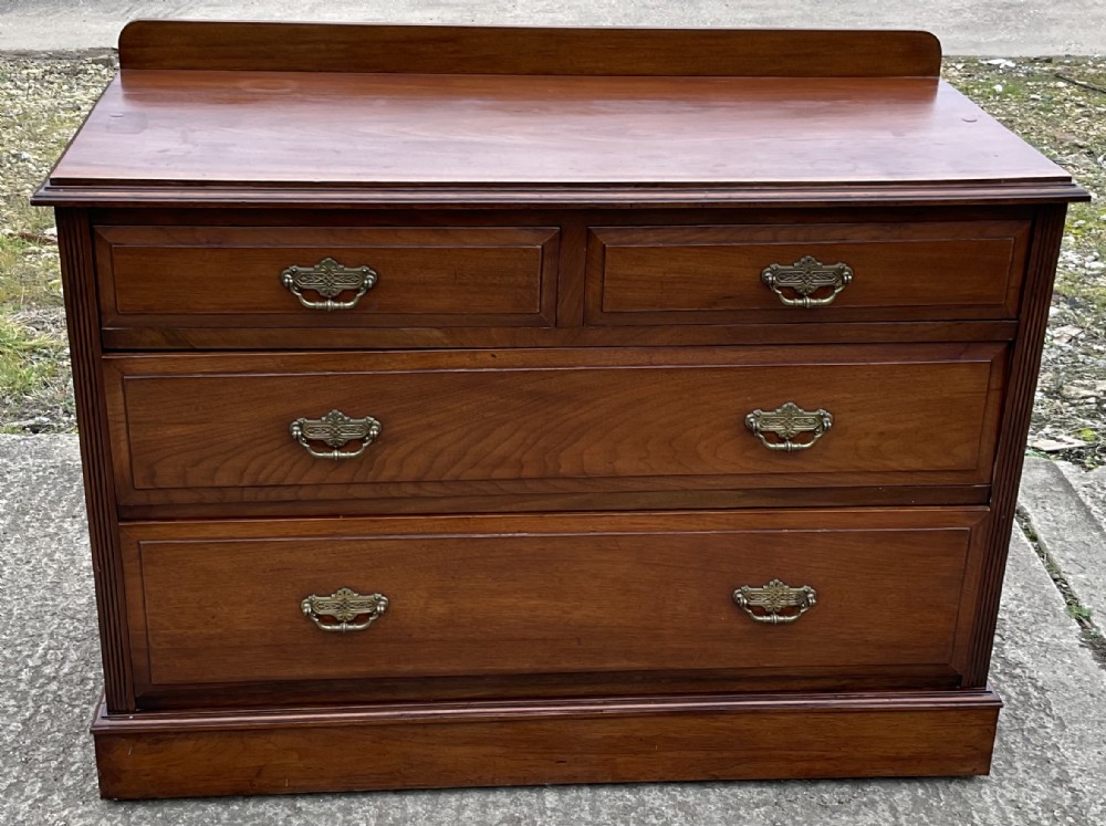 An Edwardian mahogany chest of drawers with two short drawers over two long drawers, decorated with brass drop handles and a low rear upstand.