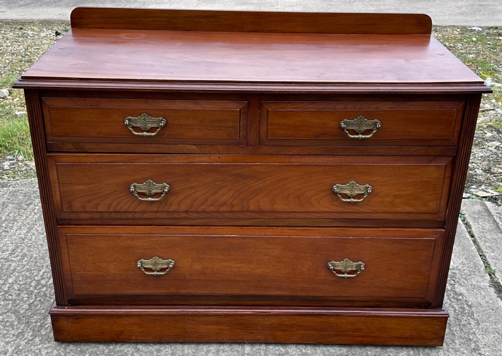 An Edwardian mahogany chest of drawers with two short drawers over two long drawers, decorated with brass drop handles and a low rear upstand. View IV
