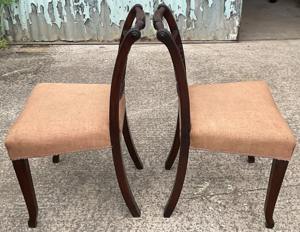 A pair of Georgian mahogany dining chairs with reeded frames, carved back rails, and beige fabric upholstered seats. View IV