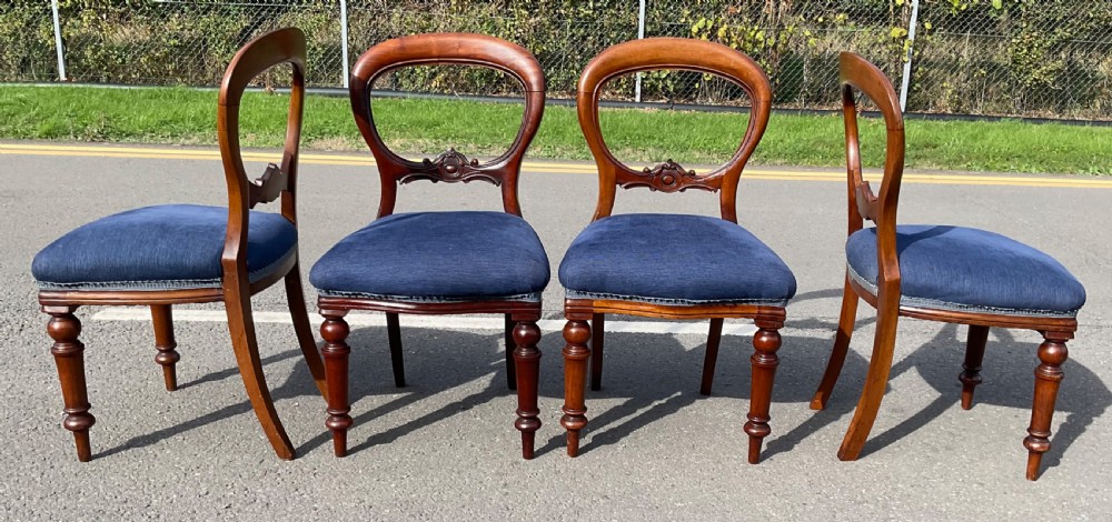 A set of four Victorian mahogany dining chairs featuring rounded balloon backs, carved horizontal mid-rails, blue fabric seats, and turned front legs. View III