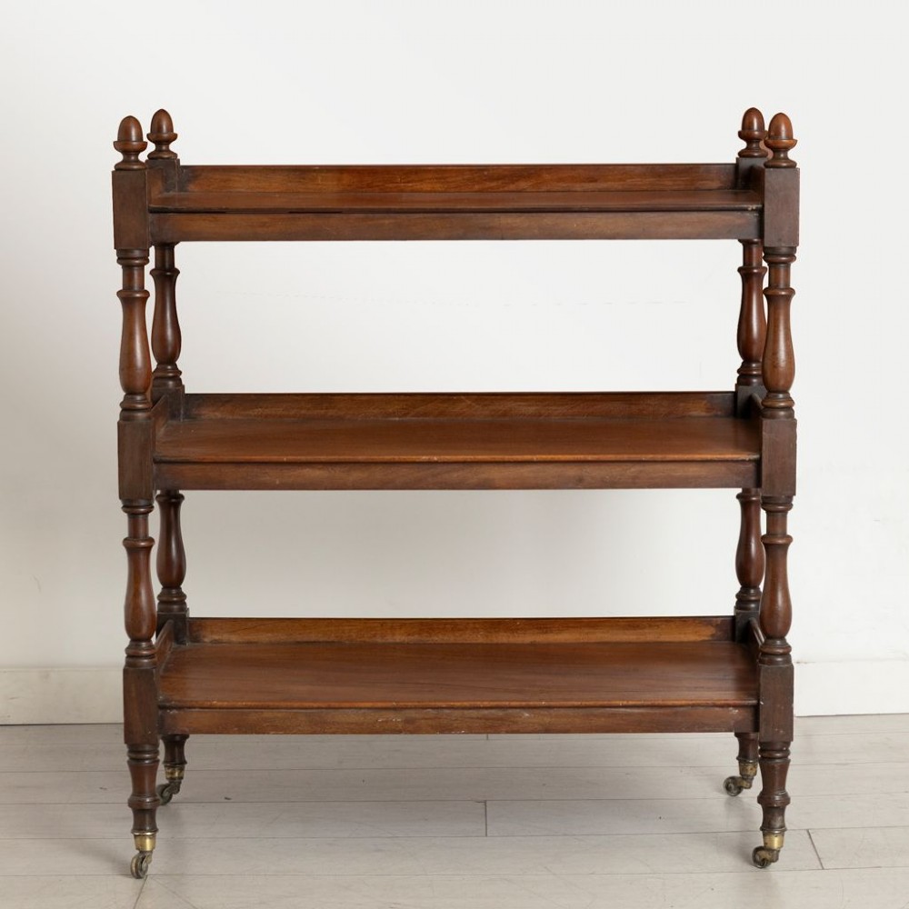 A three-tier Victorian mahogany buffet featuring turned spindle supports, urn finials, three open shelves, and brass castors. View II