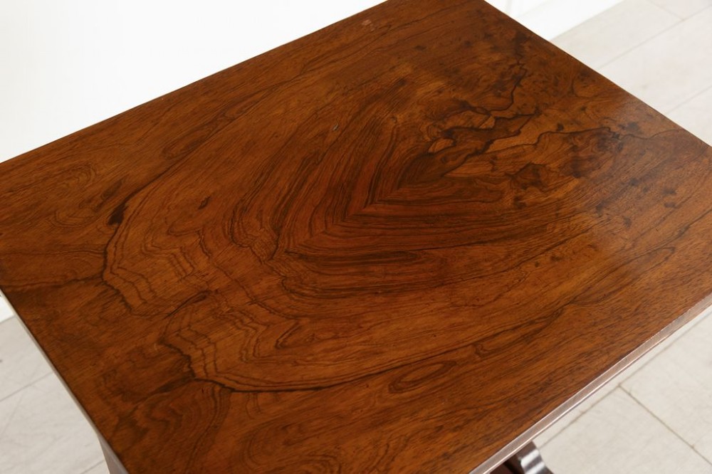 A Victorian rosewood side table featuring a single frieze drawer, shaped trestle supports, a central stretcher, and carved scroll feet fitted with brass castors. View II