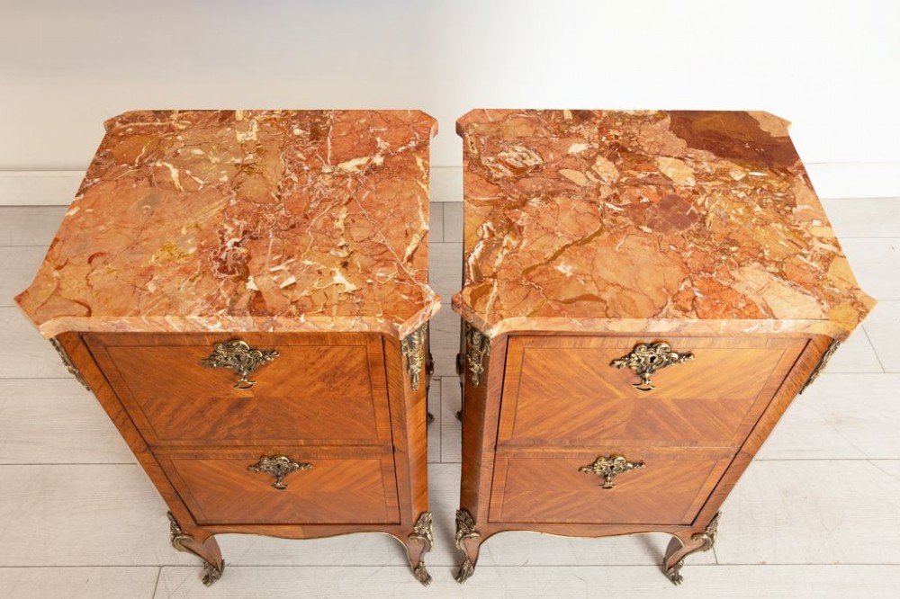 A matching pair of French 19th-century walnut and kingwood bedside cabinets featuring pink marble tops, parquetry drawer fronts, cabriole legs, and ornate brass mounts. View II