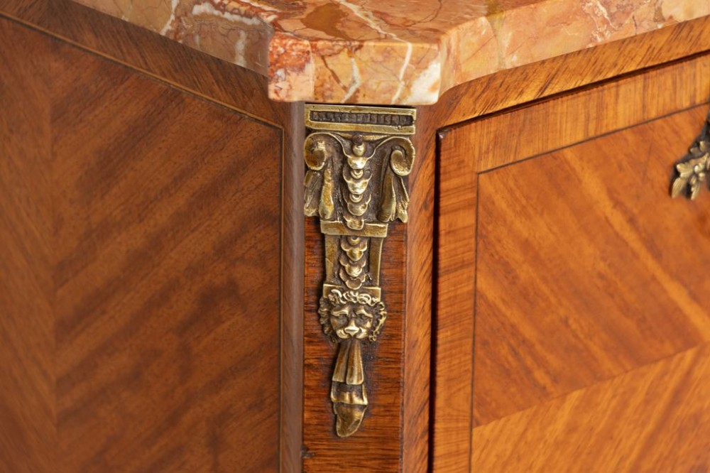 A matching pair of French 19th-century walnut and kingwood bedside cabinets featuring pink marble tops, parquetry drawer fronts, cabriole legs, and ornate brass mounts. View IV