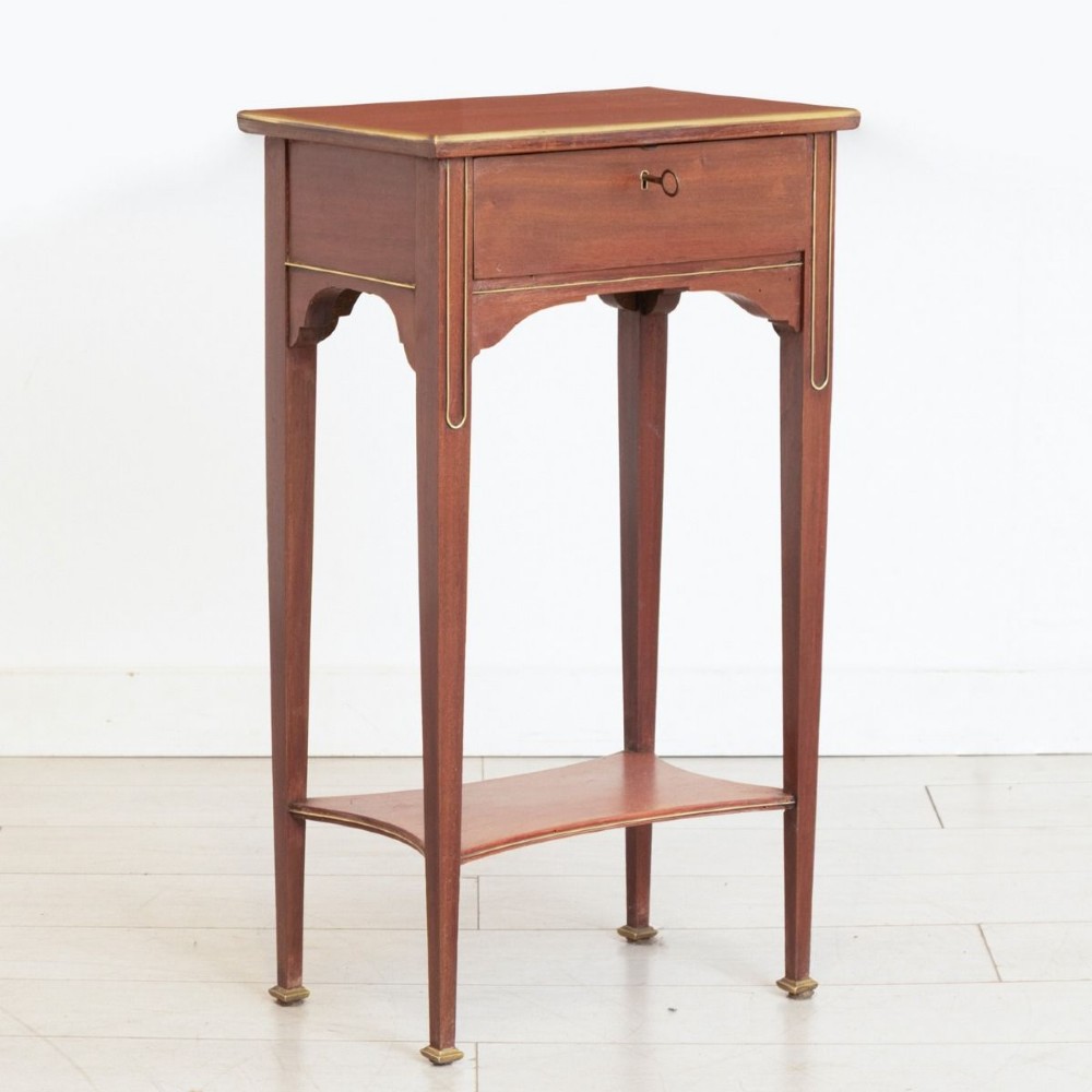 A tall French mahogany bedside table featuring a single drawer with brass stringing inlay, tapered legs, lower shelf, and brass feet.