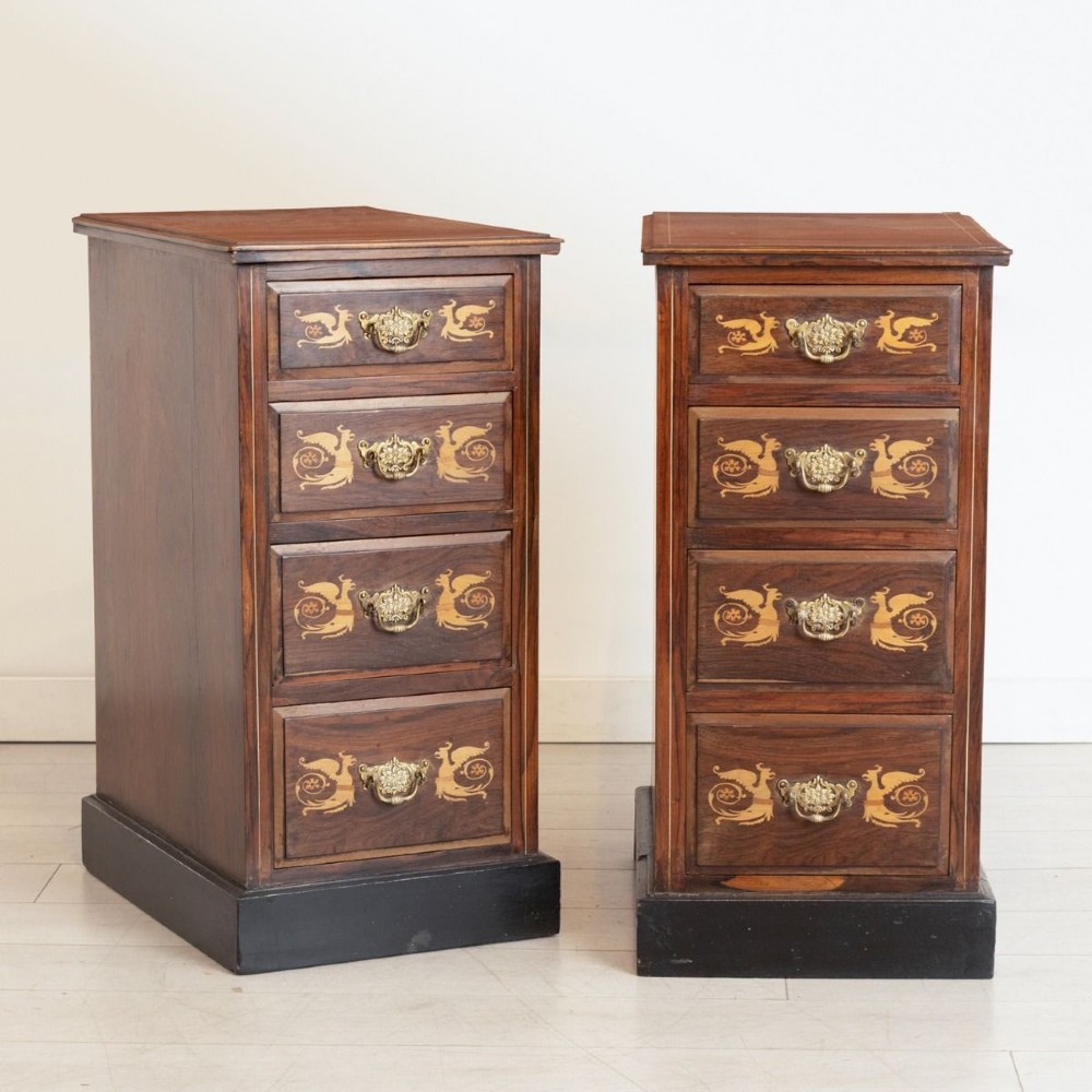 A matching pair of dark rosewood four-drawer bedside cabinets featuring floral and griffin marquetry inlays and ornate brass handles on plinth bases.