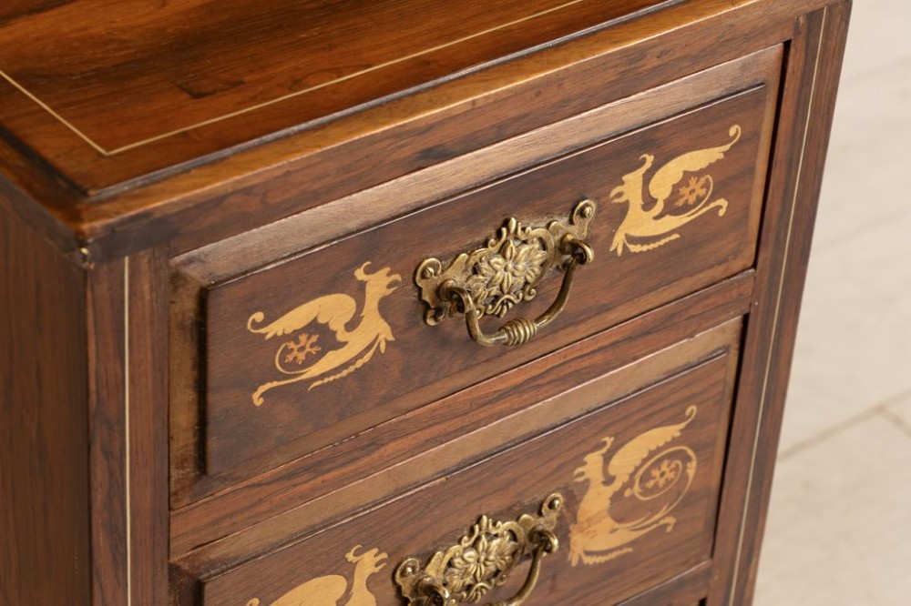 A matching pair of dark rosewood four-drawer bedside cabinets featuring floral and griffin marquetry inlays and ornate brass handles on plinth bases. View III