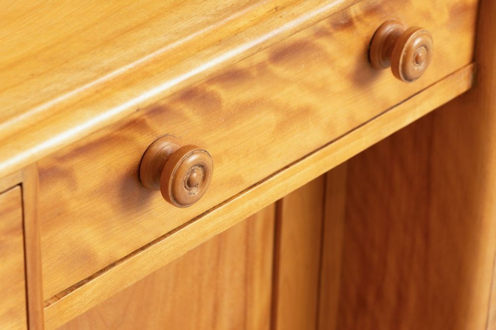 A Victorian satin birch kneehole desk featuring a low gallery top, central cupboard door, surrounding drawers, and turned wooden handles. View III