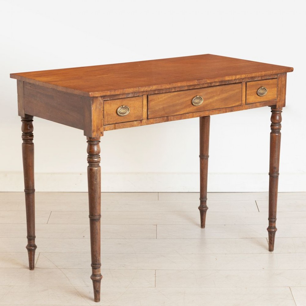 A 19th-century mahogany writing table featuring three frieze drawers with oval brass handles and four slender turned legs. View II