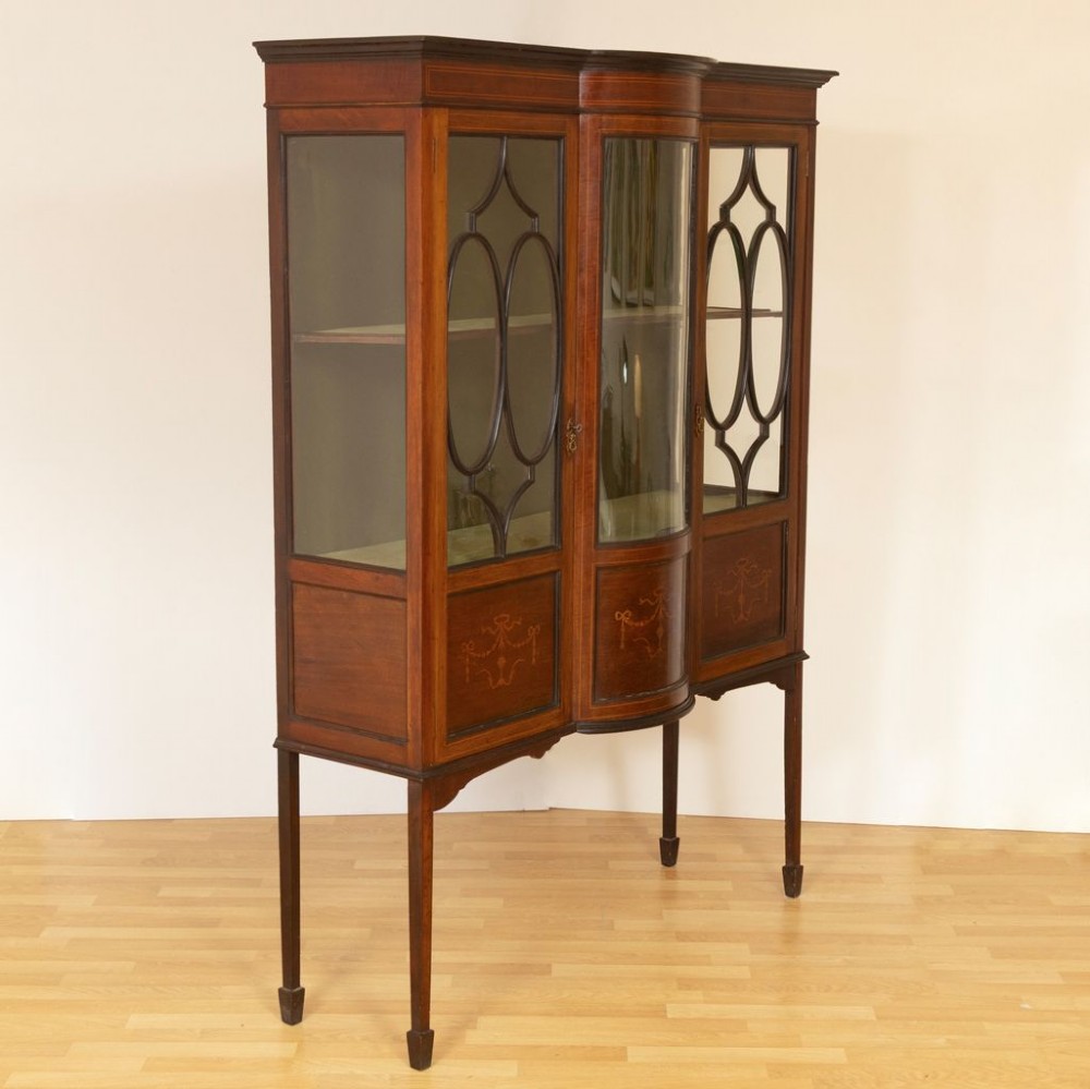 An Edwardian mahogany china cabinet featuring three glazed doors with oval astragal moulding, inlaid lower panels, and slender square legs. View II