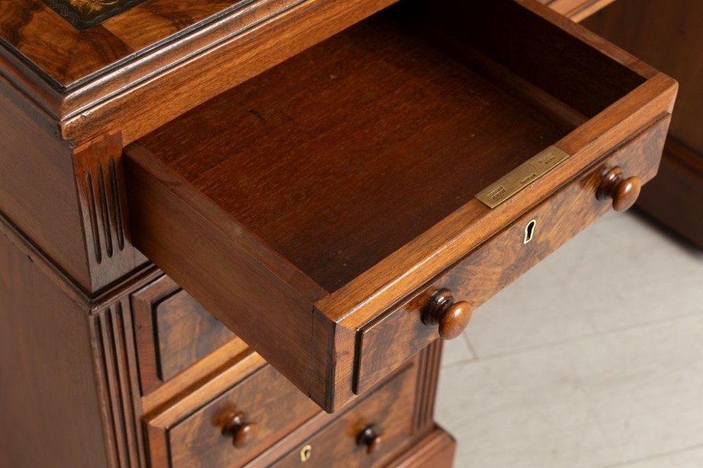 A nineteenth-century Victorian walnut pedestal desk featuring decorative burr walnut drawer fronts, turned wooden handles, a green leather writing surface, and a sturdy plinth base. View III