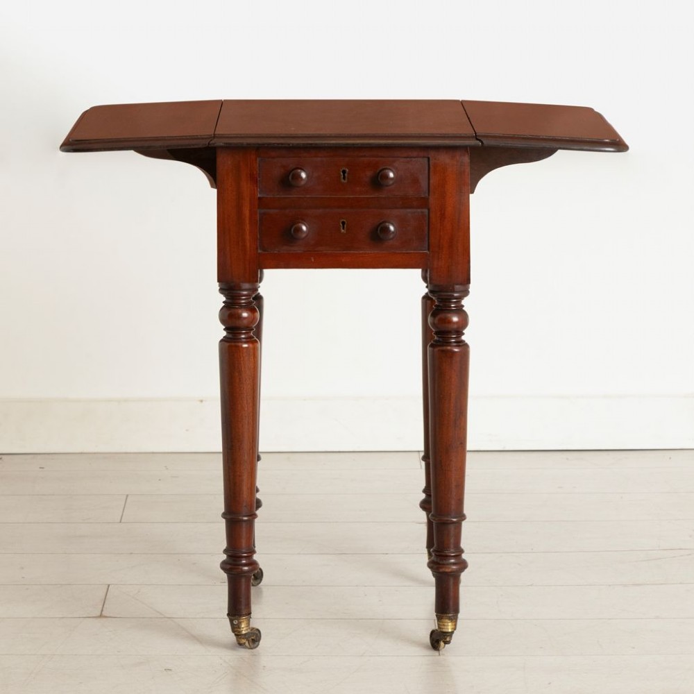 A Victorian mahogany drop-leaf side table featuring two front drawers with turned wooden knobs, ring-turned legs, and brass castors. View II