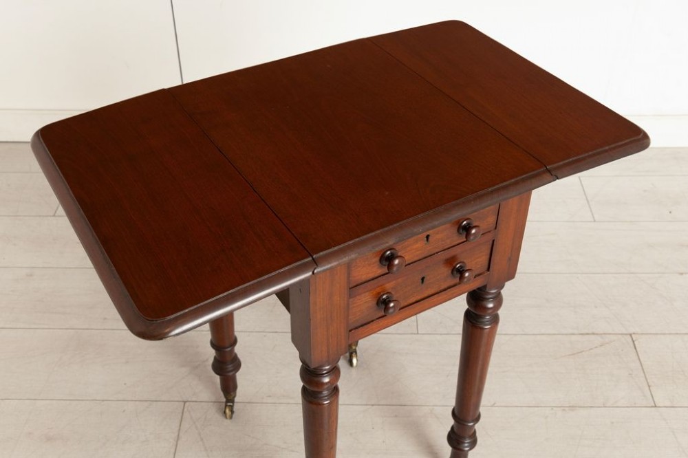 A Victorian mahogany drop-leaf side table featuring two front drawers with turned wooden knobs, ring-turned legs, and brass castors. View III