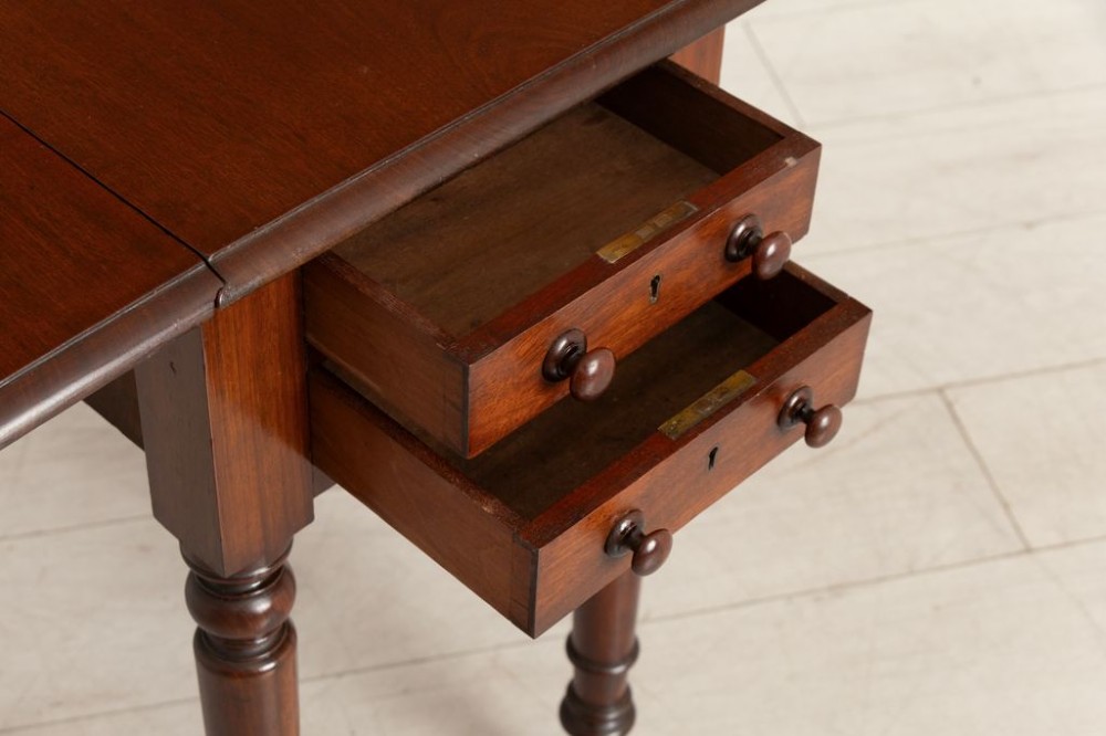 A Victorian mahogany drop-leaf side table featuring two front drawers with turned wooden knobs, ring-turned legs, and brass castors. View IV