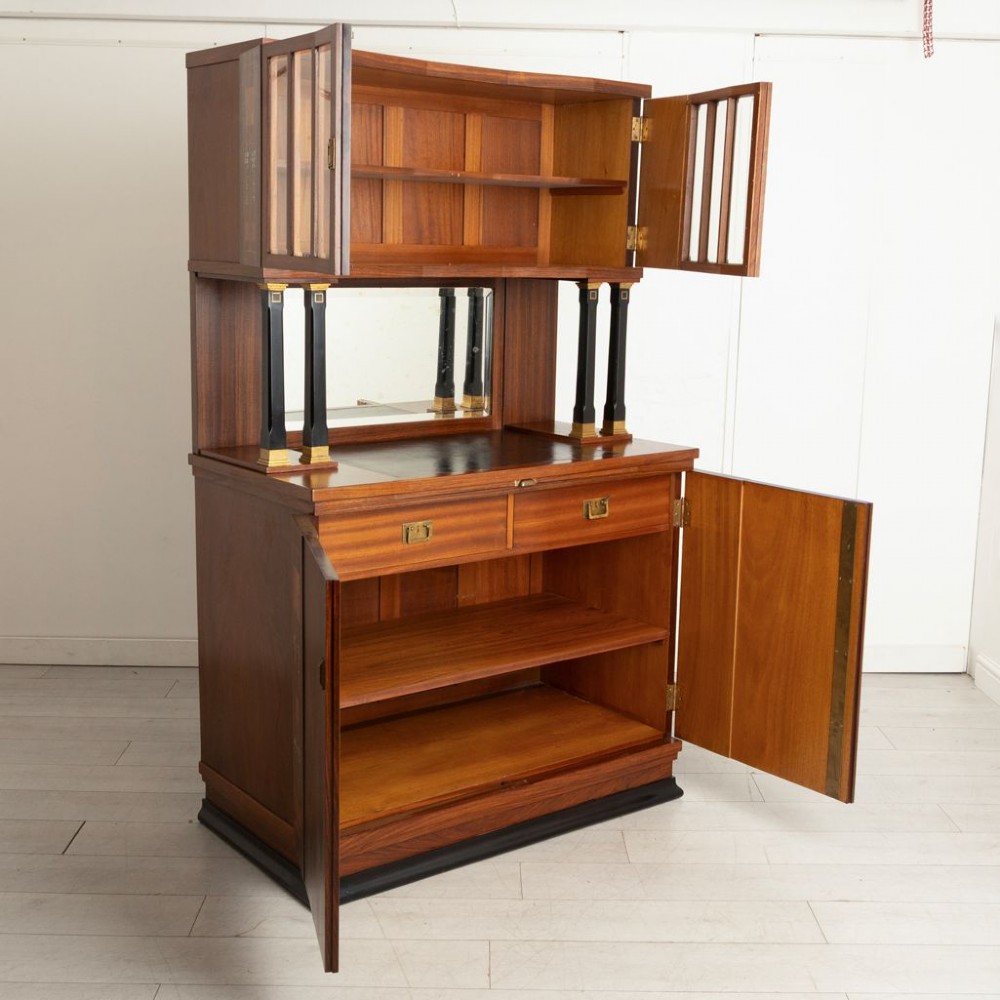 An antique Viennese Secessionist walnut display cabinet featuring geometric marquetry inlays, ebonised column supports, upper glazed doors, a central mirrored niche, and a lower two-door cupboard. View II