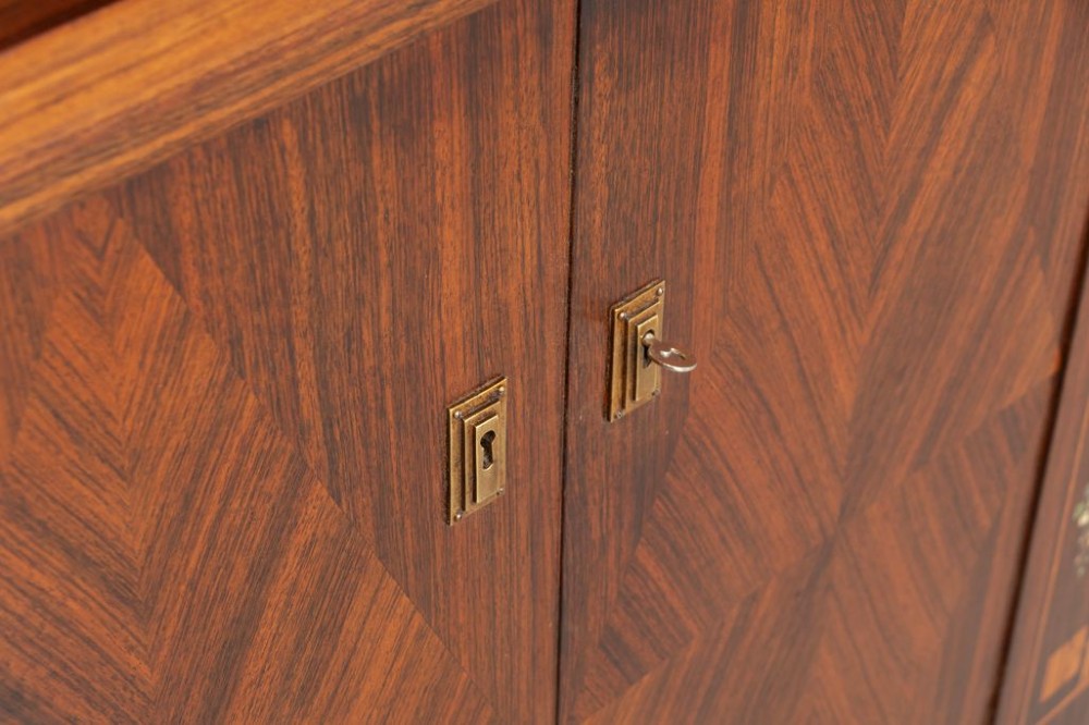 An antique Viennese Secessionist walnut display cabinet featuring geometric marquetry inlays, ebonised column supports, upper glazed doors, a central mirrored niche, and a lower two-door cupboard. View VII