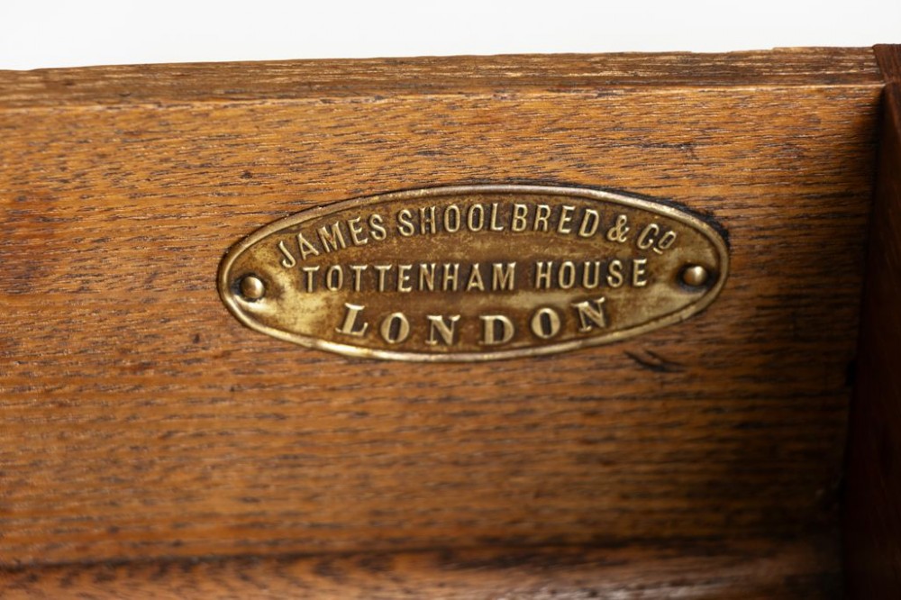 An antique Victorian octagonal oak library table with a green leather inset writing top, relief-carved frieze drawers, turned legs, and a carved X-stretcher. View IV