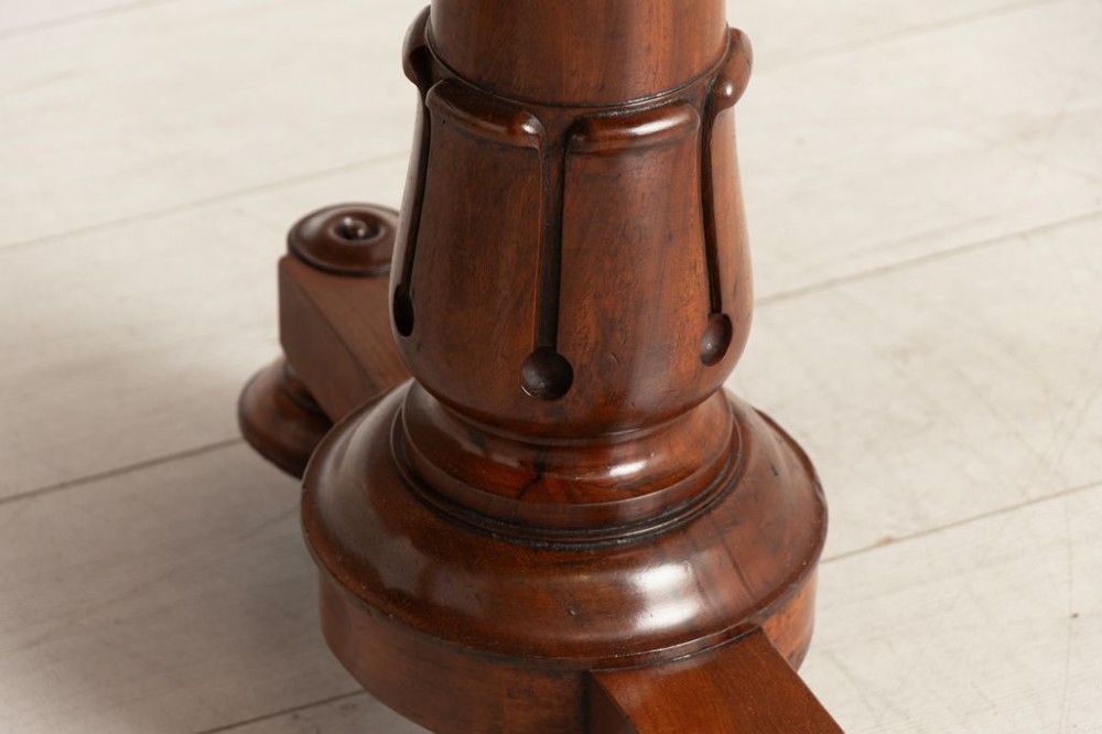 A Regency mahogany library table with a rectangular tan leather writing top, frieze drawers, turned column supports, and brass castors. View III