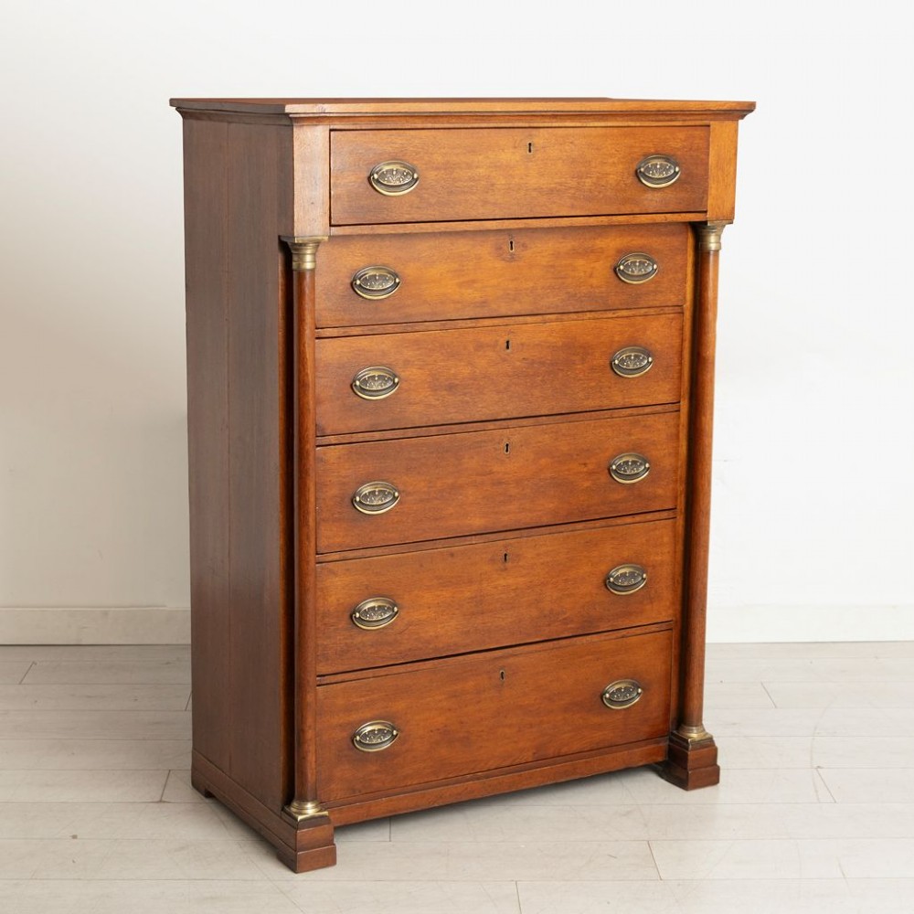 A tall mid-19th century French oak chest of drawers featuring six stacked drawers, brass oval drop handles, keyhole escutcheons, and flanking columns with brass accents. View II