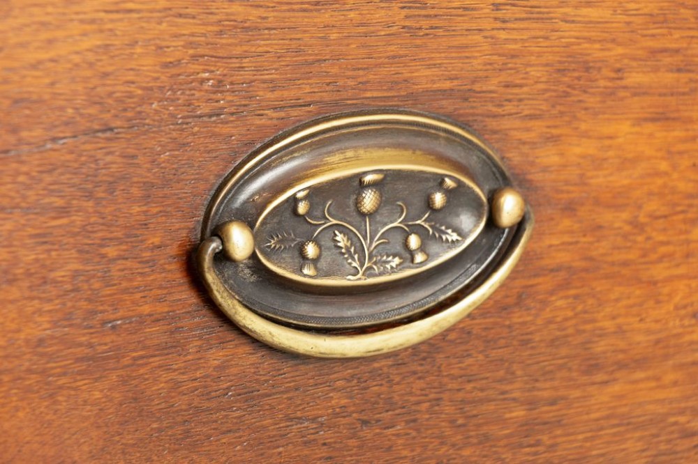 A tall mid-19th century French oak chest of drawers featuring six stacked drawers, brass oval drop handles, keyhole escutcheons, and flanking columns with brass accents. View III