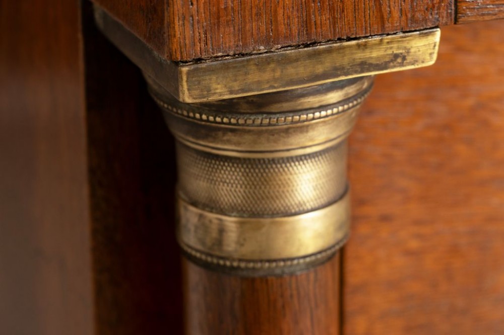 A tall mid-19th century French oak chest of drawers featuring six stacked drawers, brass oval drop handles, keyhole escutcheons, and flanking columns with brass accents. View IV