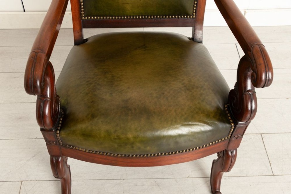 A Regency mahogany library chair featuring olive green leather upholstery with brass stud trim, carved scroll arms, and shaped legs. View III