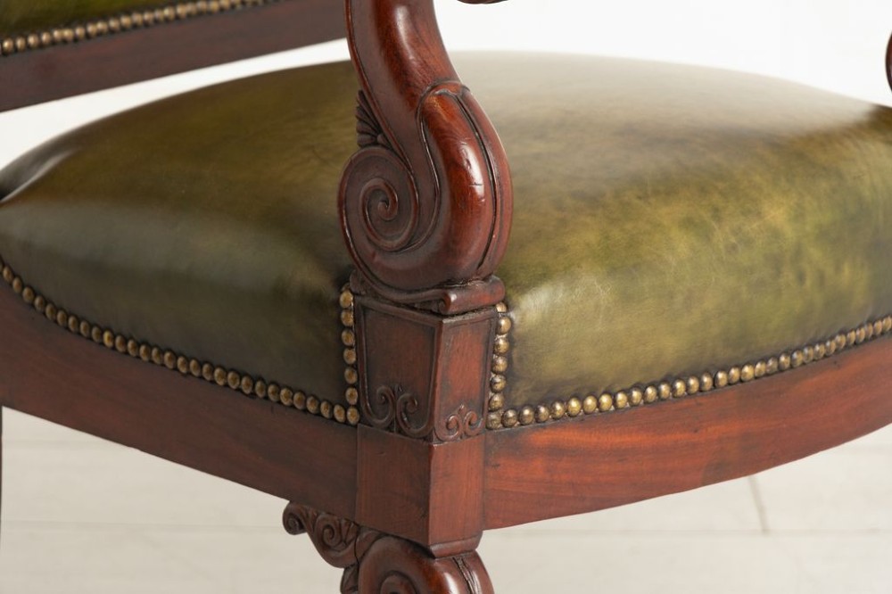 A Regency mahogany library chair featuring olive green leather upholstery with brass stud trim, carved scroll arms, and shaped legs. View IV