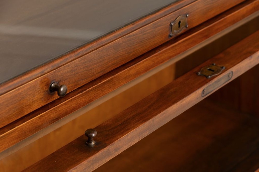An Edwardian oak three-tier sectional bookcase featuring up-and-over glazed doors, an arched pediment top, and a base drawer with wooden knobs. View III