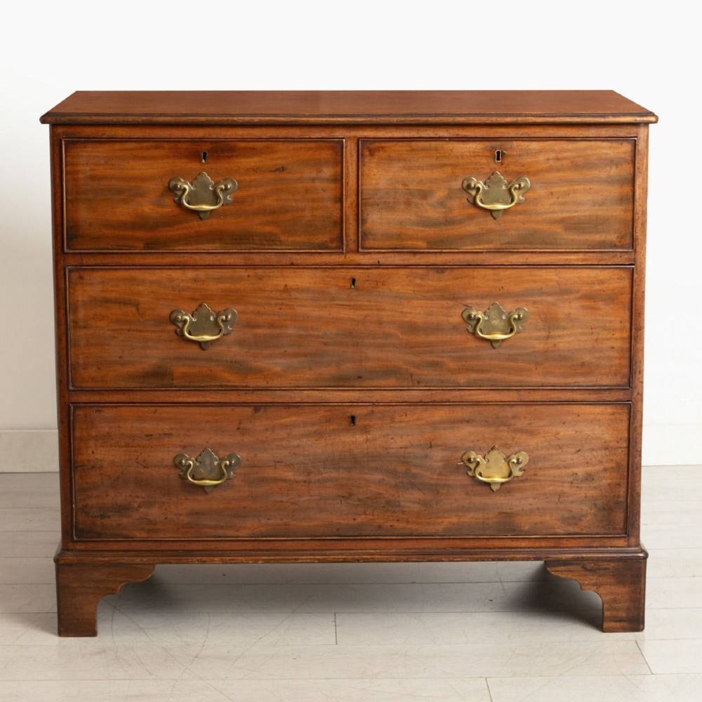 A late nineteenth-century mahogany chest of drawers featuring two short upper drawers and two long lower drawers with brass handles and shaped bracket feet.