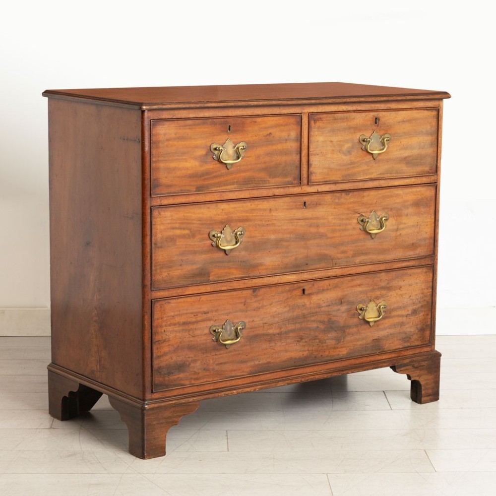 A late nineteenth-century mahogany chest of drawers featuring two short upper drawers and two long lower drawers with brass handles and shaped bracket feet. View II