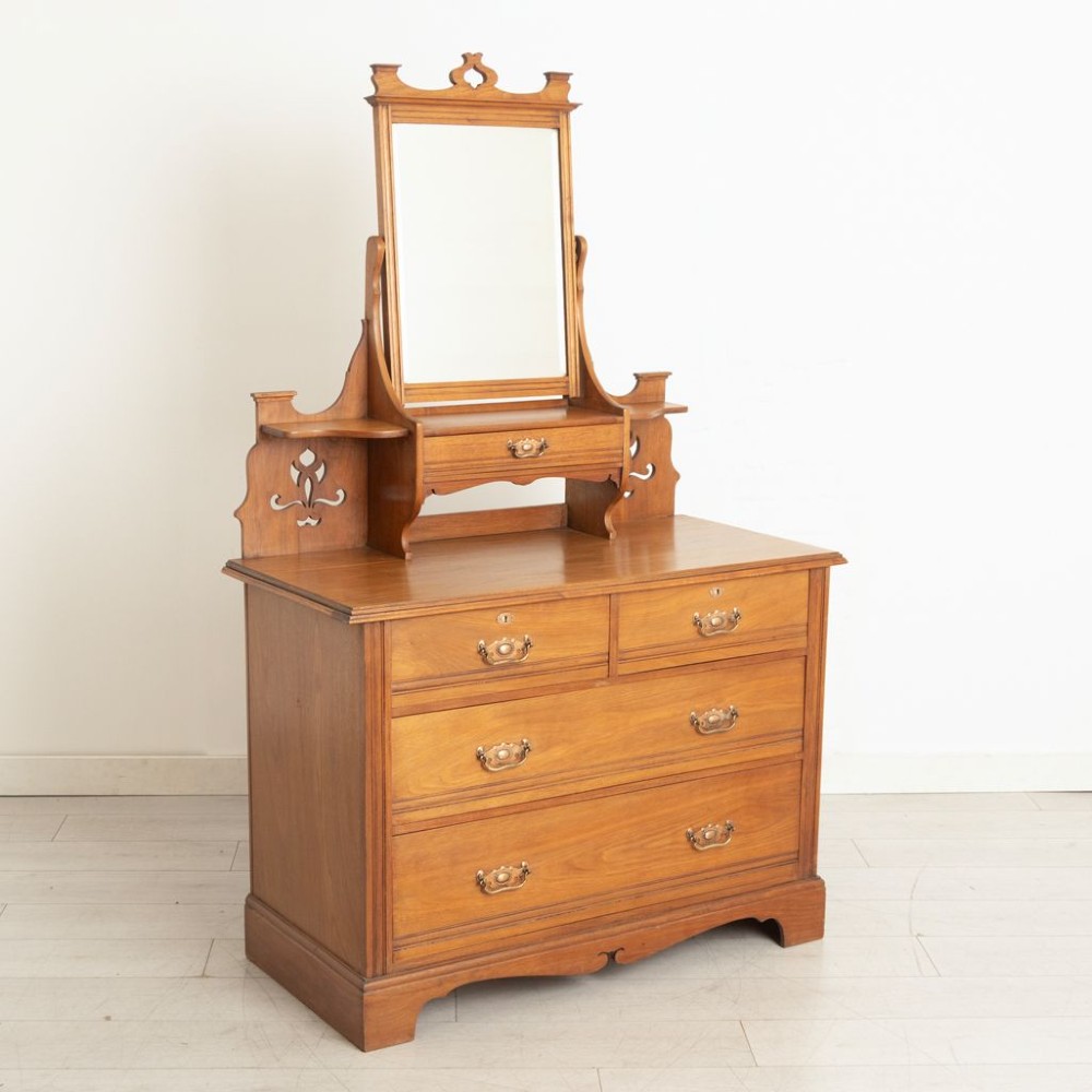 An Arts and Crafts walnut dressing chest featuring two short over two long drawers, a mirror superstructure, and decorative pierced cut-outs. View II