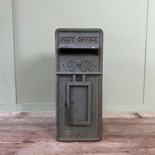 fig 1. A cast iron George VI post box with a raised GR Royal cypher alongside a tall matching metal pedestal stand.