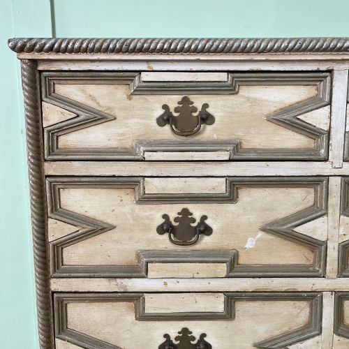 fig 1. An Edwardian painted chest of drawers featuring eight drawer fronts decorated with geometric panel mouldings, drop handles, and rope-twist edge detailing.