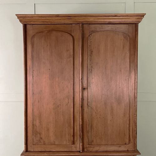 fig 1. An antique Victorian pine cupboard on chest featuring a top section with two arched panel doors above three drawers with turned wooden handles.