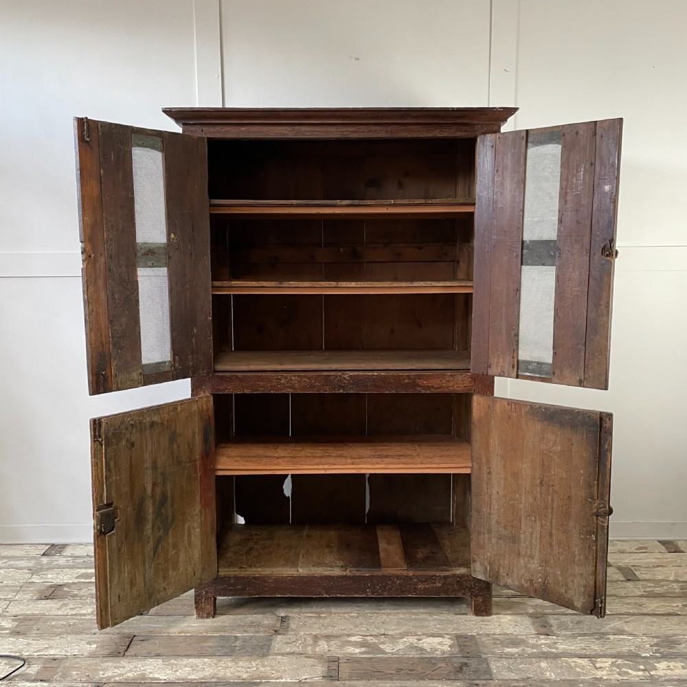 A late 18th-century dark brown painted pine food cupboard with arched mesh upper doors and fielded panel lower doors. View II