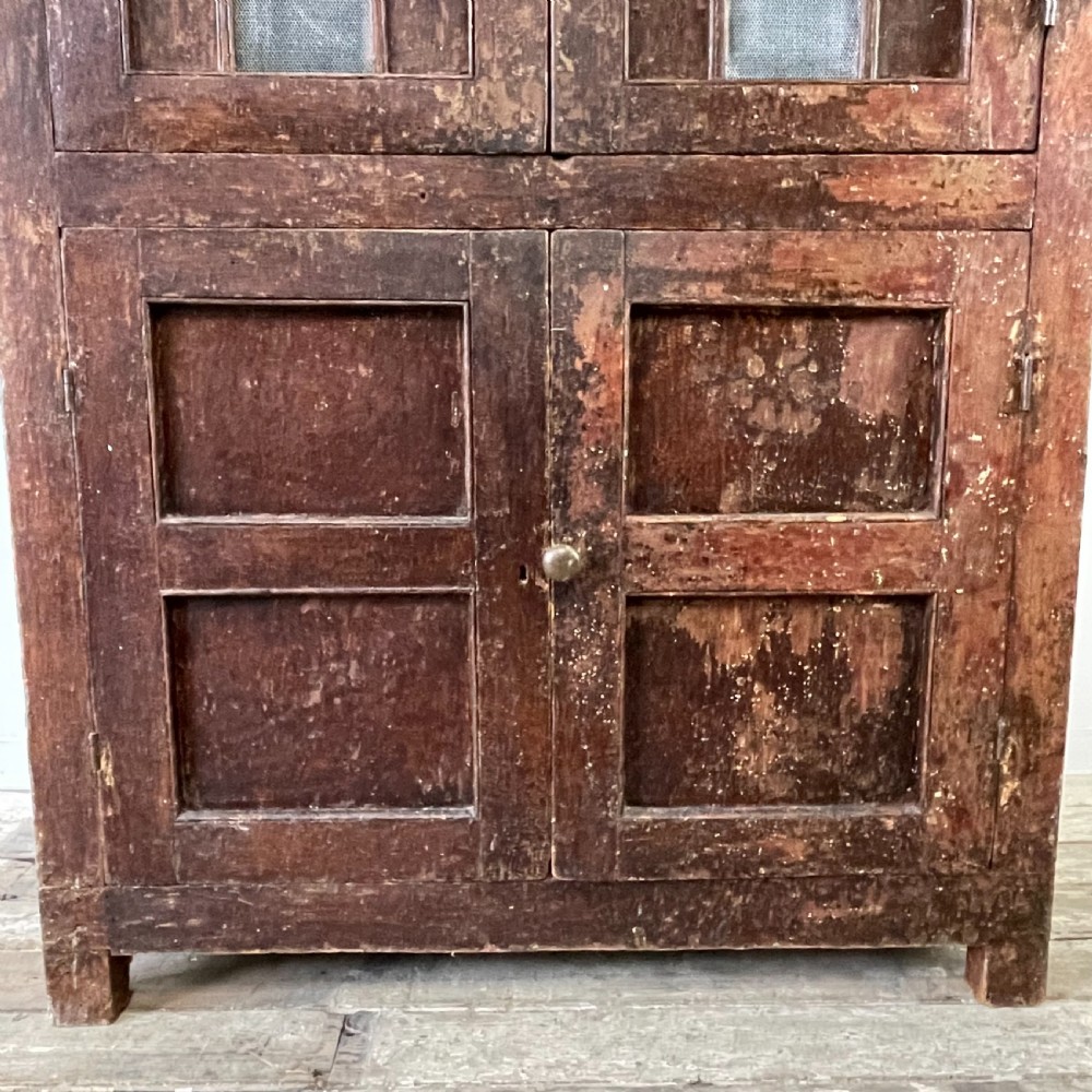 A late 18th-century dark brown painted pine food cupboard with arched mesh upper doors and fielded panel lower doors. View VI