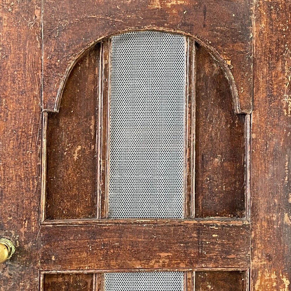 A late 18th-century dark brown painted pine food cupboard with arched mesh upper doors and fielded panel lower doors. View VIII