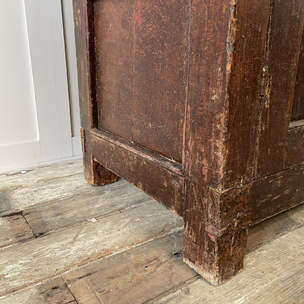 A late 18th-century dark brown painted pine food cupboard with arched mesh upper doors and fielded panel lower doors. View X