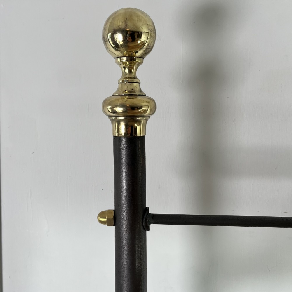 A tall Victorian-style black metal frame display stand featuring three timber slatted shelves, decorative brass finials at the top corners, and scrolled foot supports. View VII