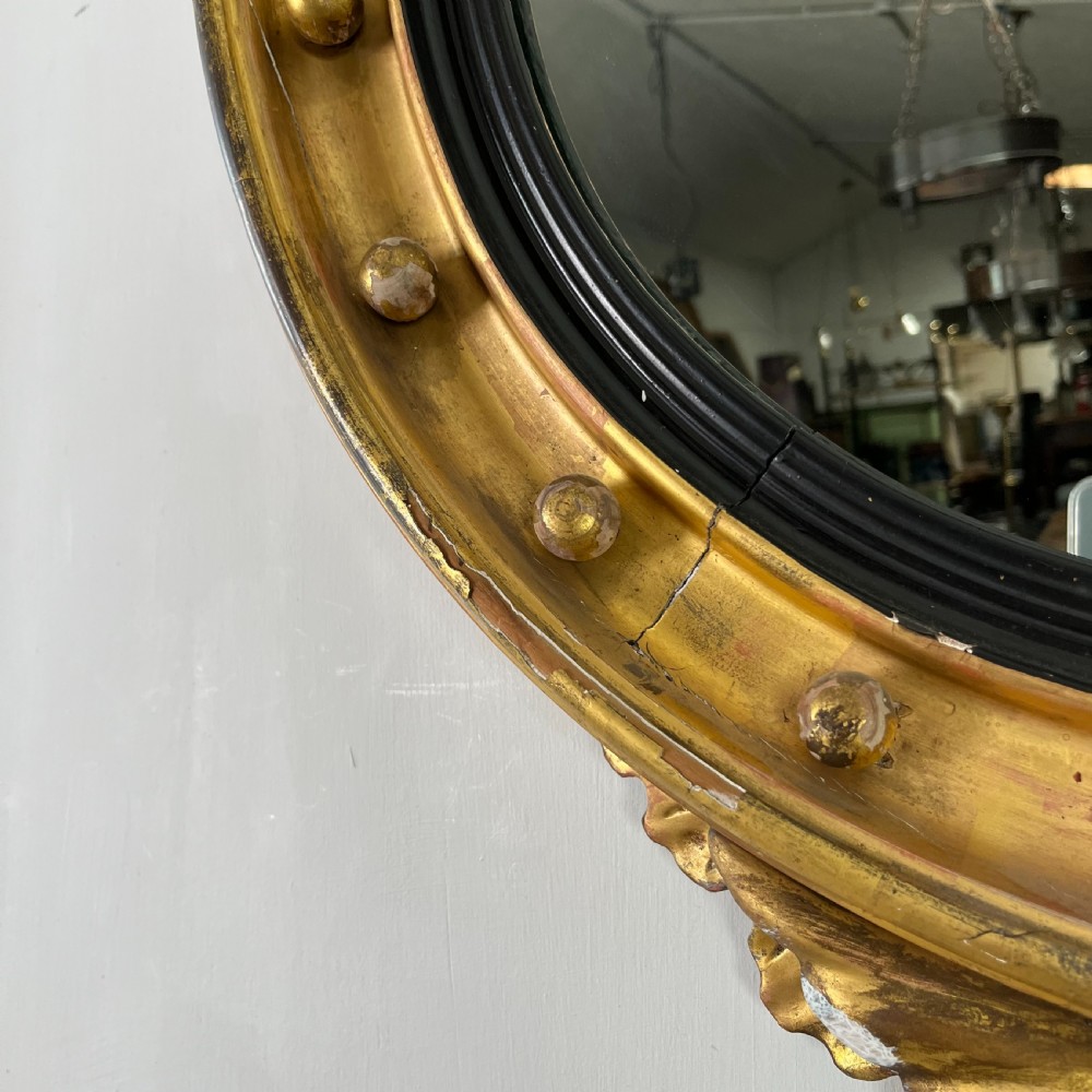 A circular carved giltwood convex wall mirror surmounted by a carved eagle crest with spread wings and an acanthus leaf apron. View III