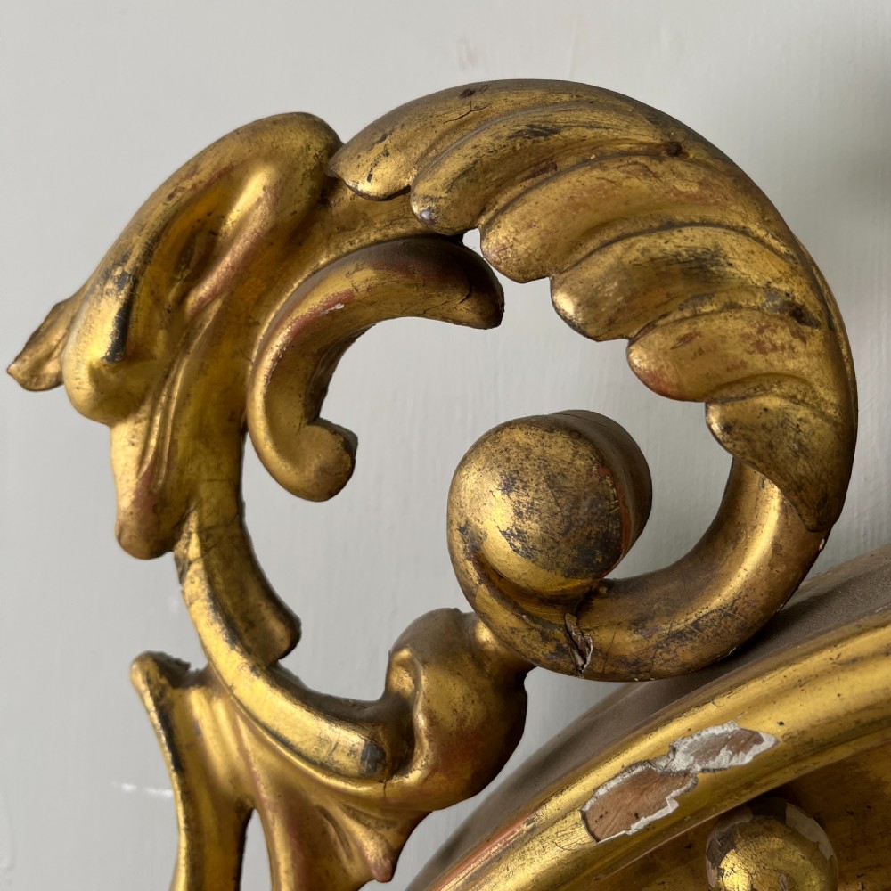 A circular carved giltwood convex wall mirror surmounted by a carved eagle crest with spread wings and an acanthus leaf apron. View X