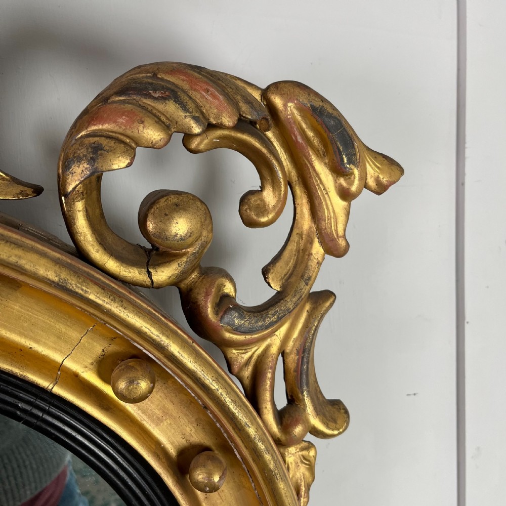 A circular carved giltwood convex wall mirror surmounted by a carved eagle crest with spread wings and an acanthus leaf apron. View XI