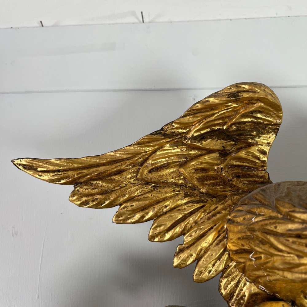 A circular carved giltwood convex wall mirror surmounted by a carved eagle crest with spread wings and an acanthus leaf apron. View XIII