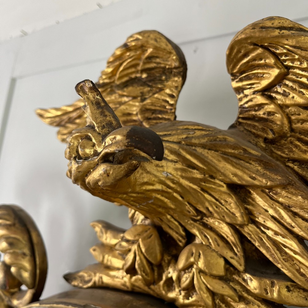 A circular carved giltwood convex wall mirror surmounted by a carved eagle crest with spread wings and an acanthus leaf apron. View XVI