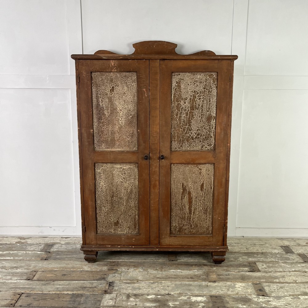 A nineteenth-century two-door pine cupboard featuring distressed crackle-glaze panel doors and a shaped cresting rail.