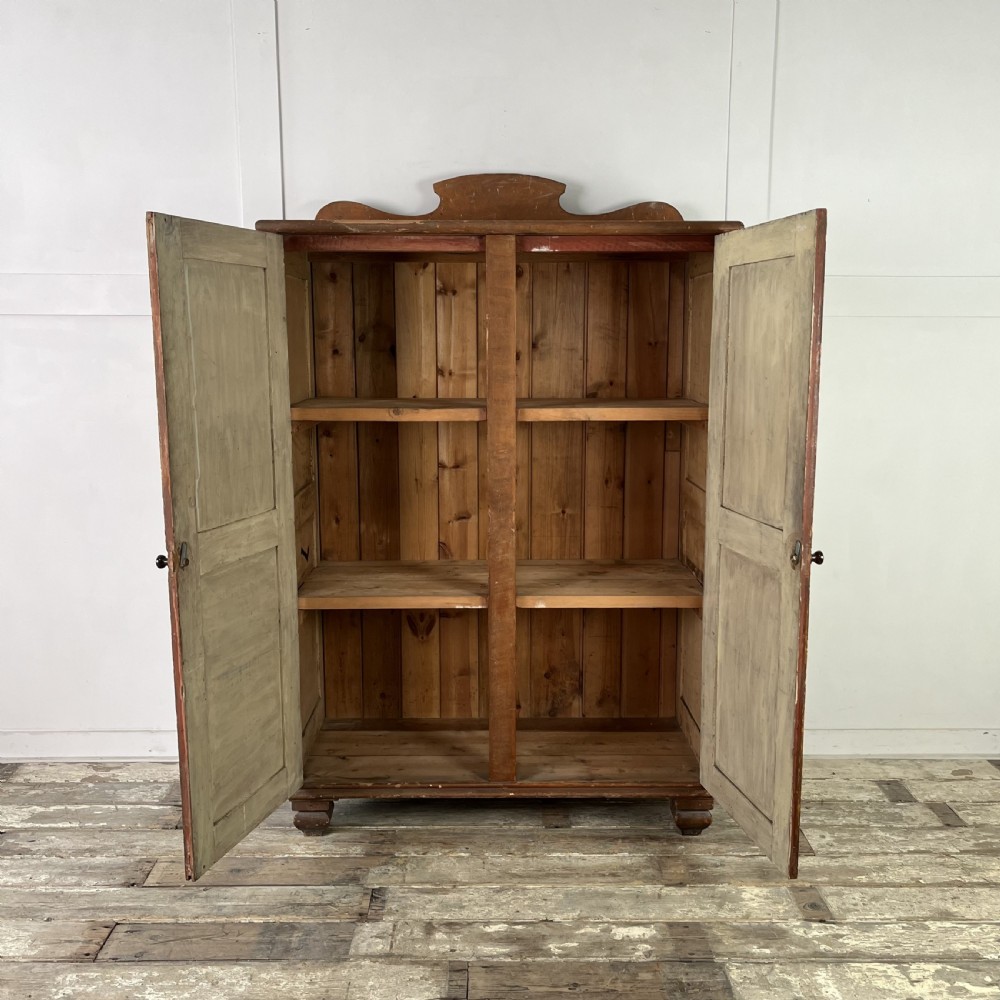 A nineteenth-century two-door pine cupboard featuring distressed crackle-glaze panel doors and a shaped cresting rail. View II