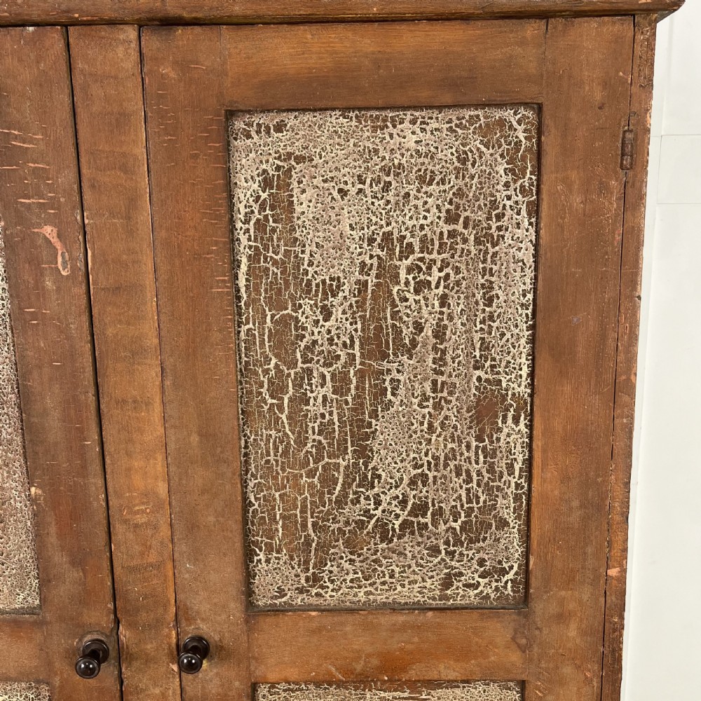 A nineteenth-century two-door pine cupboard featuring distressed crackle-glaze panel doors and a shaped cresting rail. View V